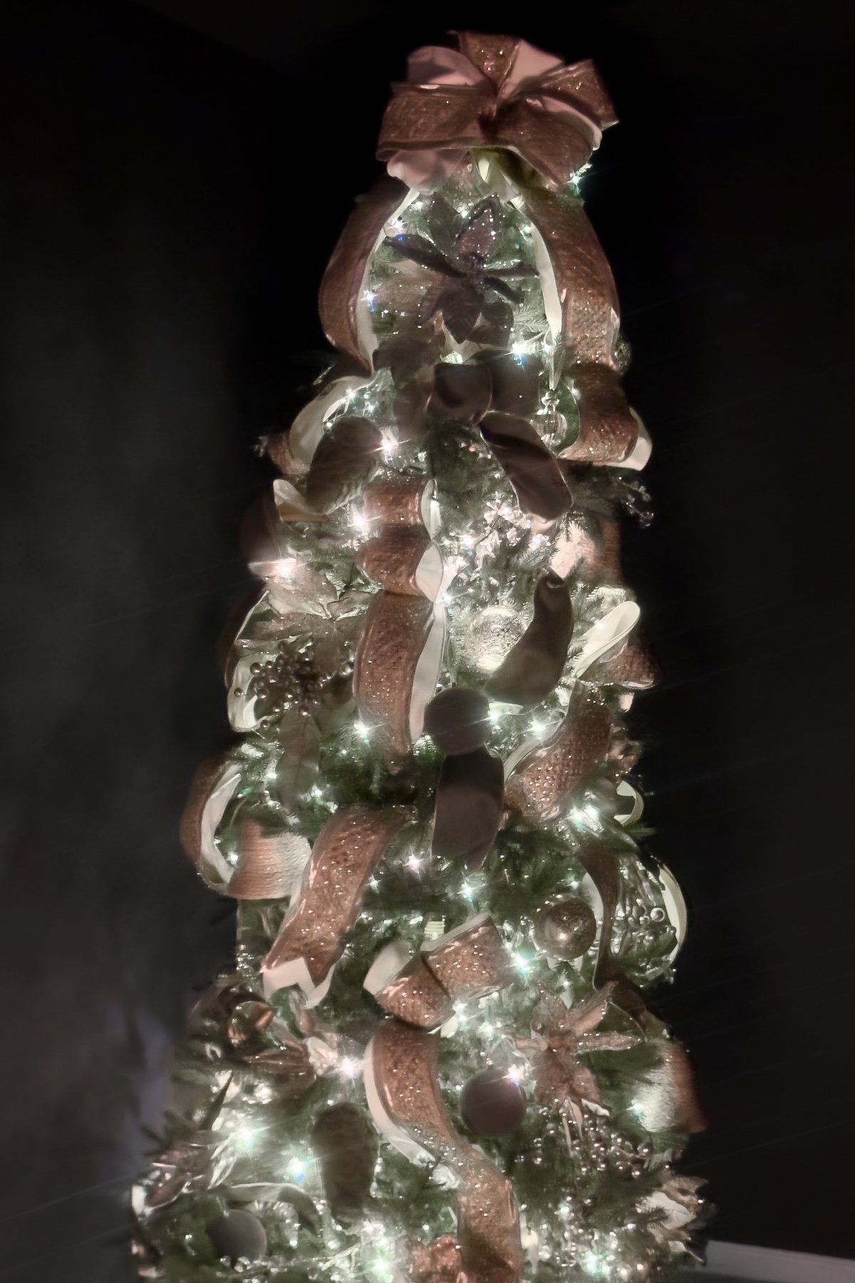 Luxury residential Christmas tree installation with layered ribbon and soft metallic accents