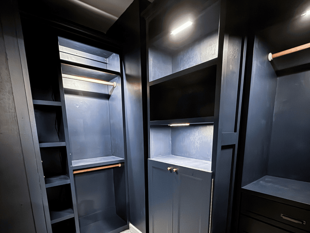 Custom moody blue closet with built-in cabinetry, brass hardware, and tailored storage designed by Enchanted Journey Design